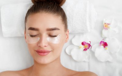 Woman With Patches Under Eyes, Relaxing In Spa Center With Flowers Nearby